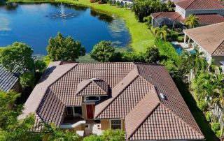 Barrel tile roof with hips, valleys and ridge caps on a single story Southwest Florida home beside a pond with a fountain